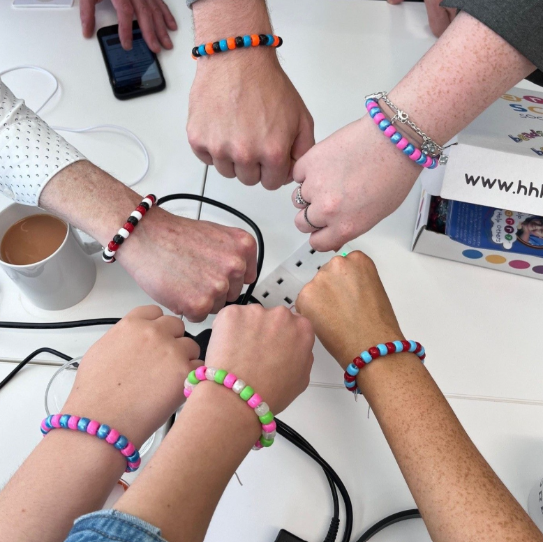 Members of the Smile Education team holding up Help Harry Help Others bracelets